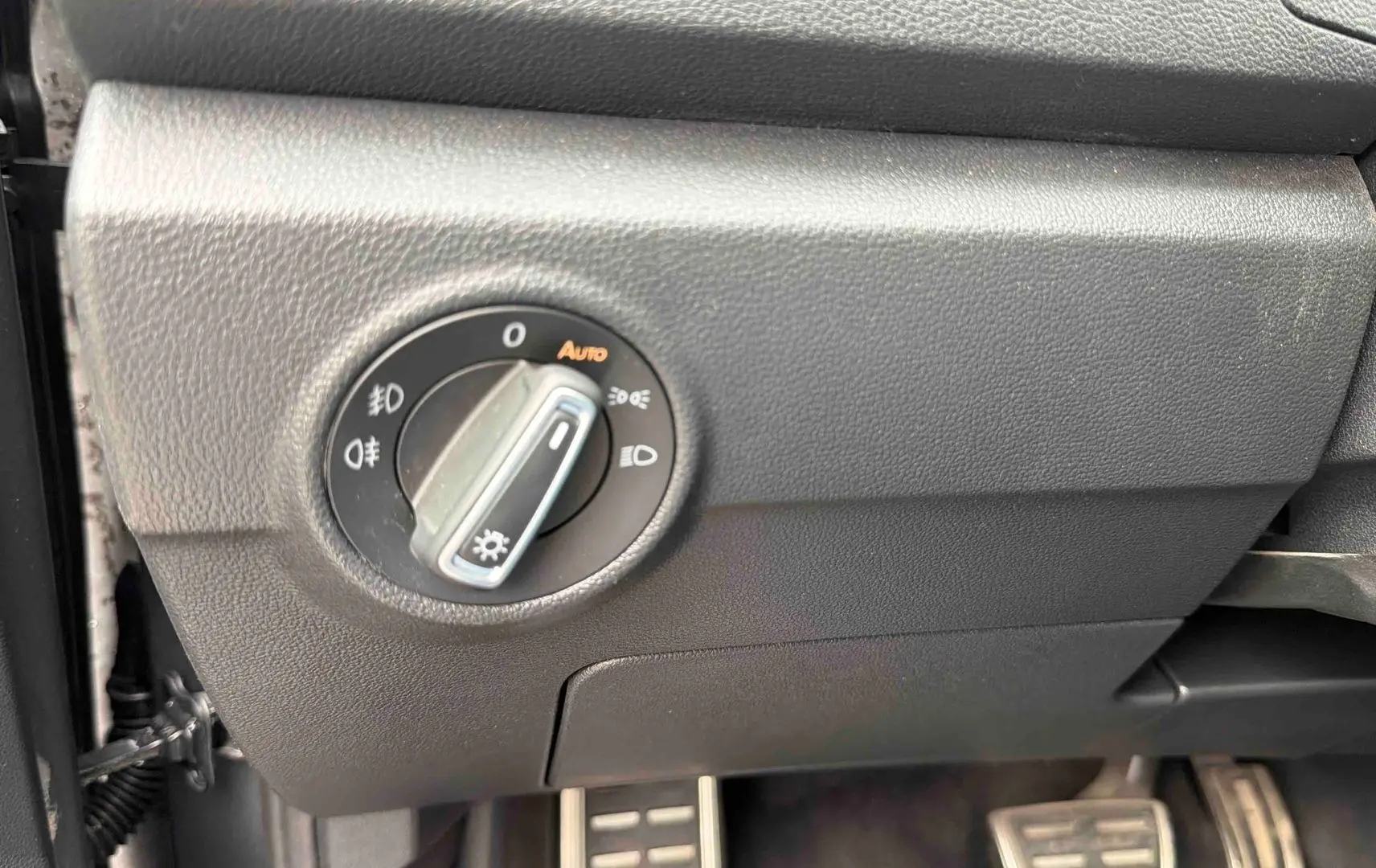 Gros plan sur la commande des feux à gauche du volant dans l’habitacle du Volkswagen T-Roc gris Indium.