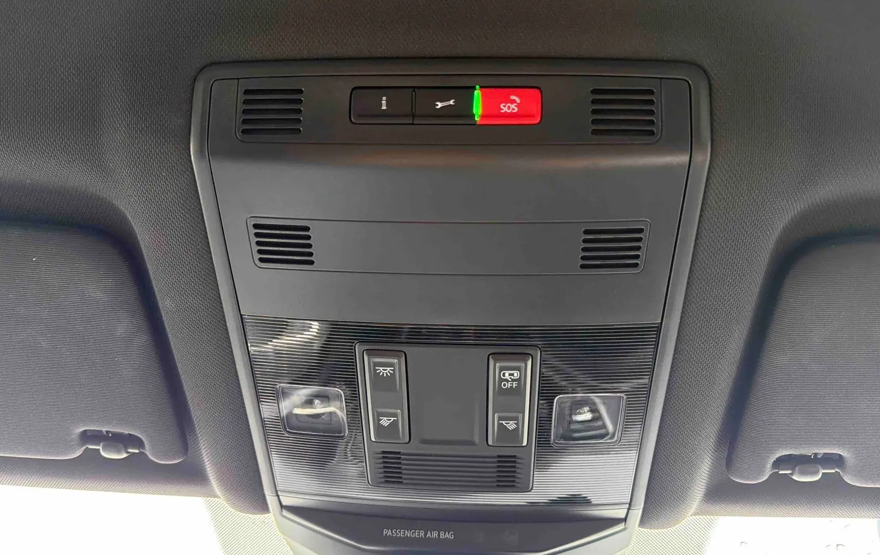 Vue intérieure du plafonnier du Volkswagen T-Roc gris Indium, avec commandes d’éclairage et bouton SOS rouge.
