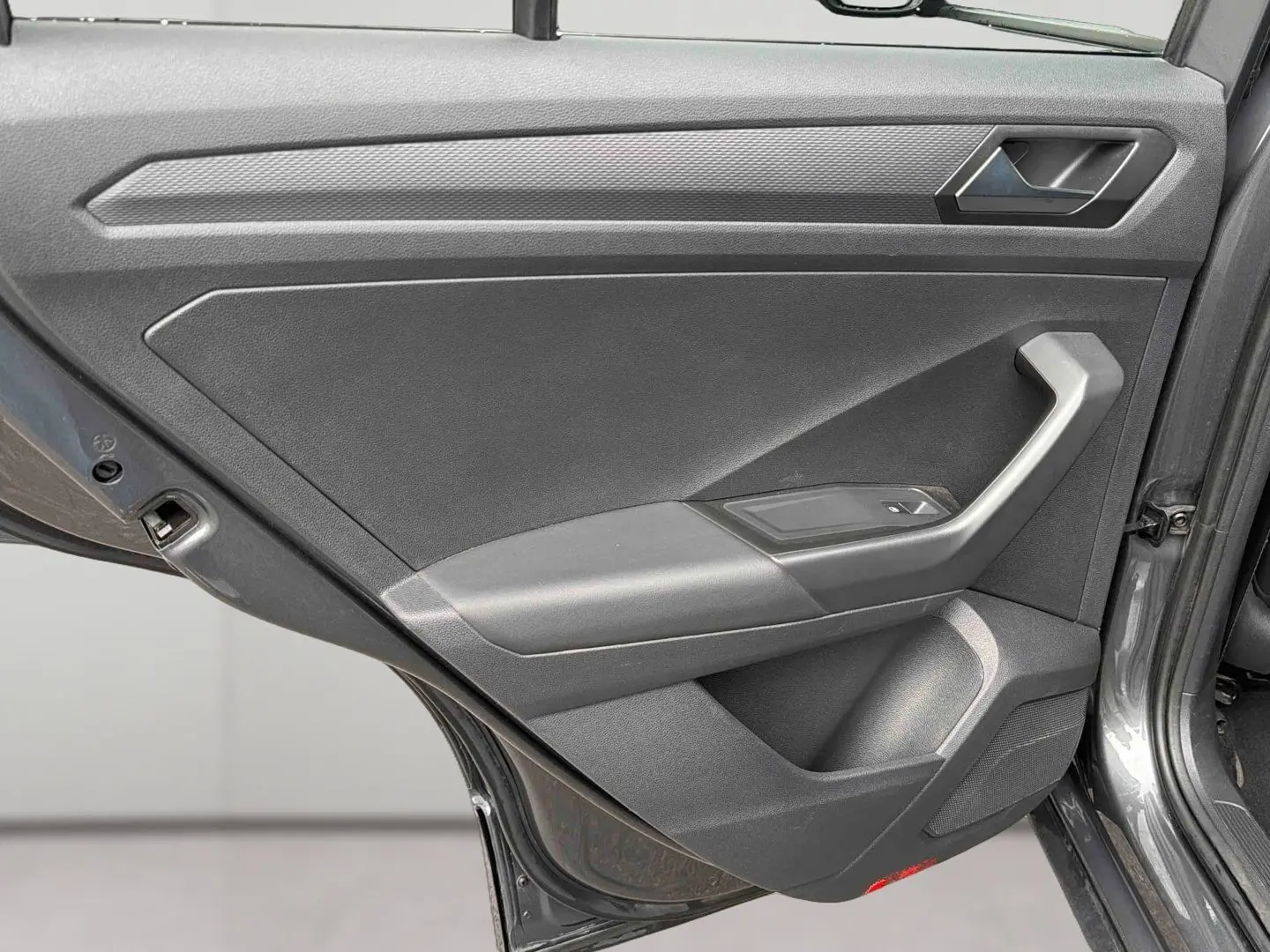 Vue rapprochée de la porte arrière gauche gris Indium métal du Volkswagen T-Roc 2020 avec accoudoir et commande de vitre.
