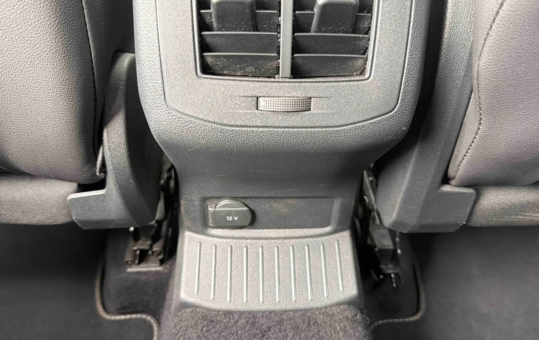 Détail de la console arrière grise avec prise 12V et aérateur entre les sièges arrière du Volkswagen T-Roc gris Indium.