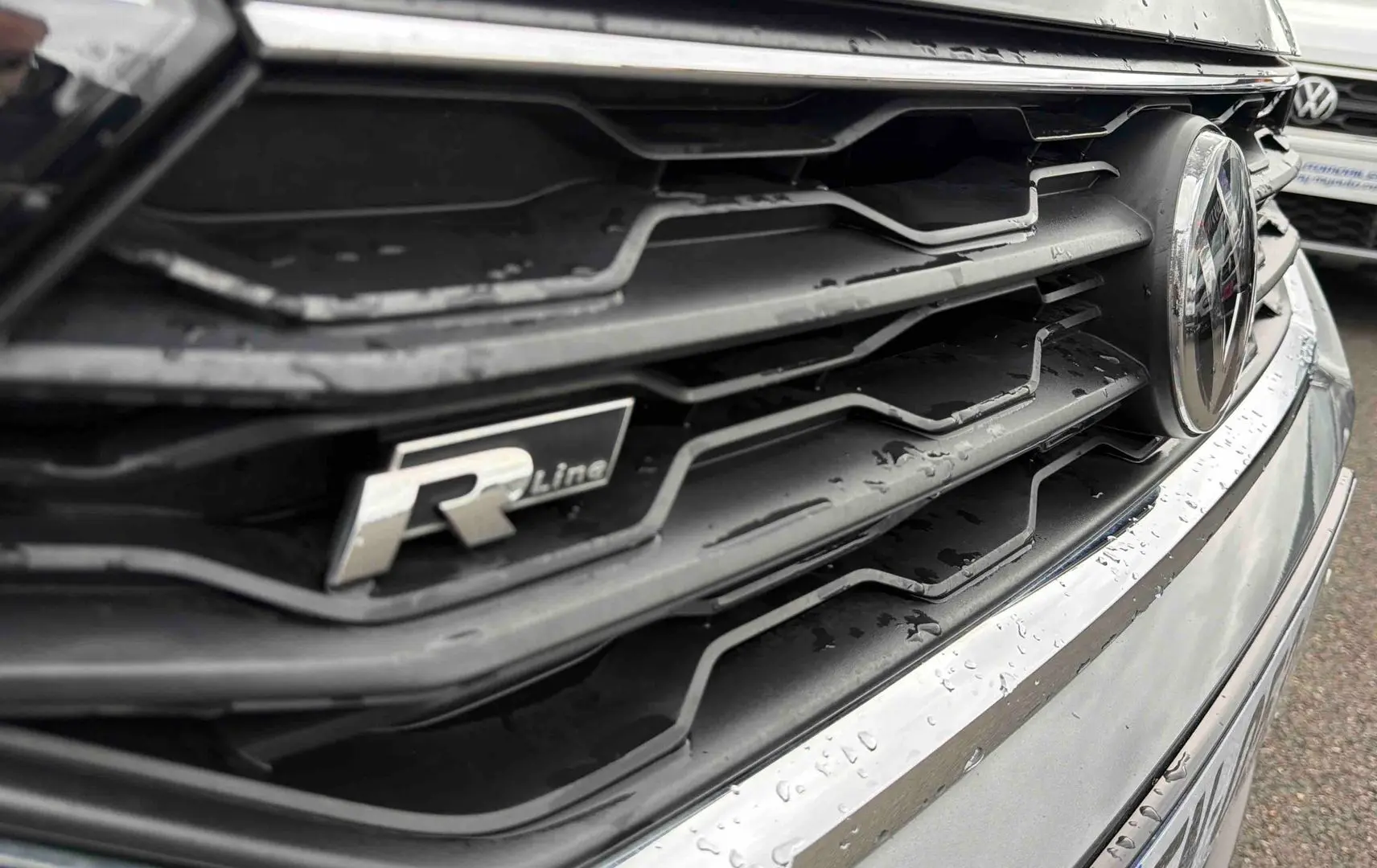 Gros plan sur la calandre avant grise indium métallisée du Volkswagen T-Roc 2020 avec logo R-Line et badge VW.