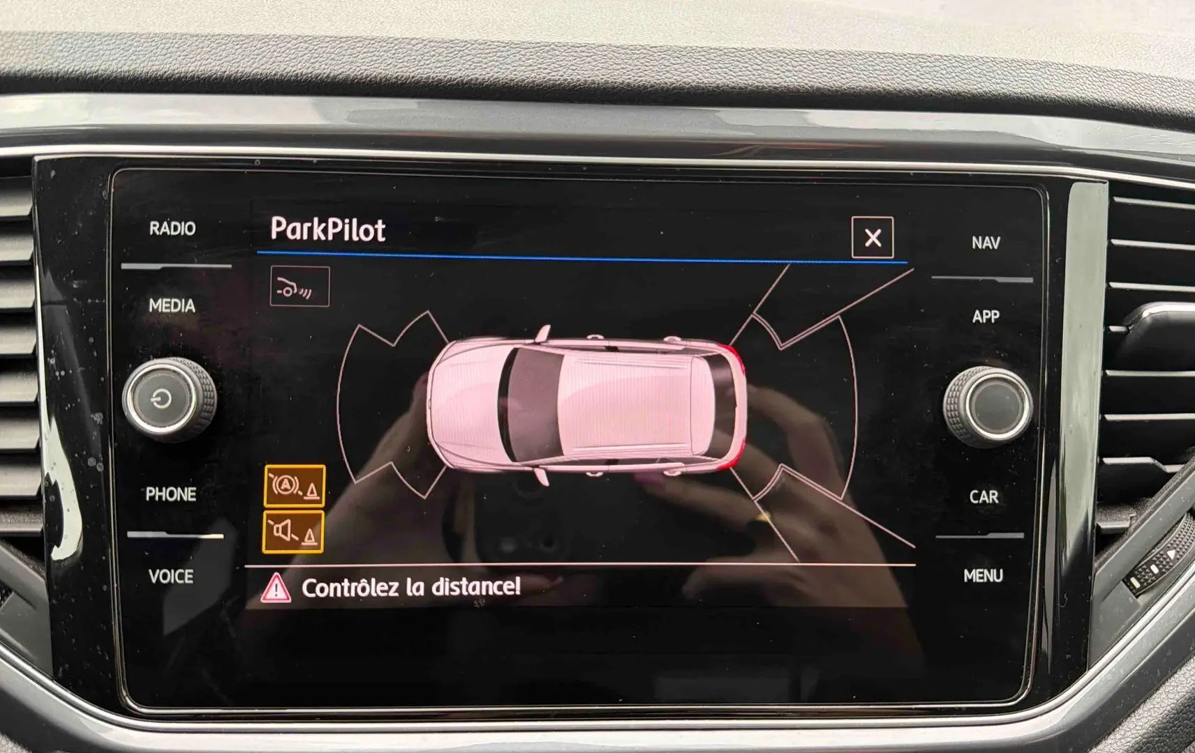 Écran tactile intérieur affichant l'aide au stationnement ParkPilot d'un Volkswagen T-Roc gris Indium Metal.