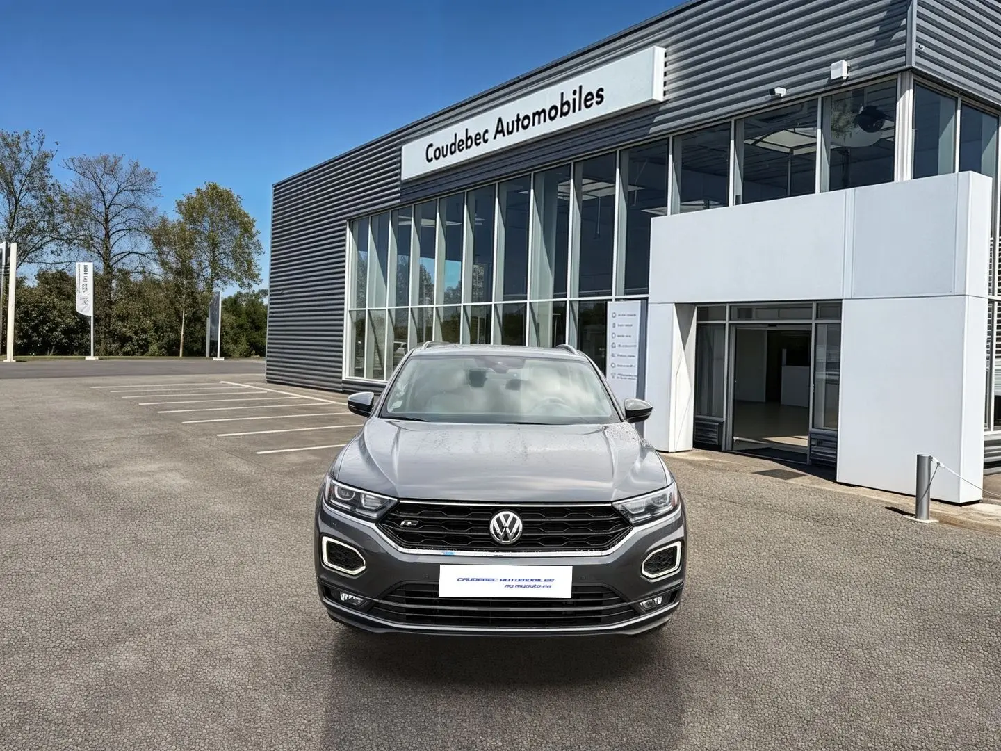 Volkswagen T-Roc gris Indium Metal vue de face, avec calandre R-Line et éclairage LED distinctif.