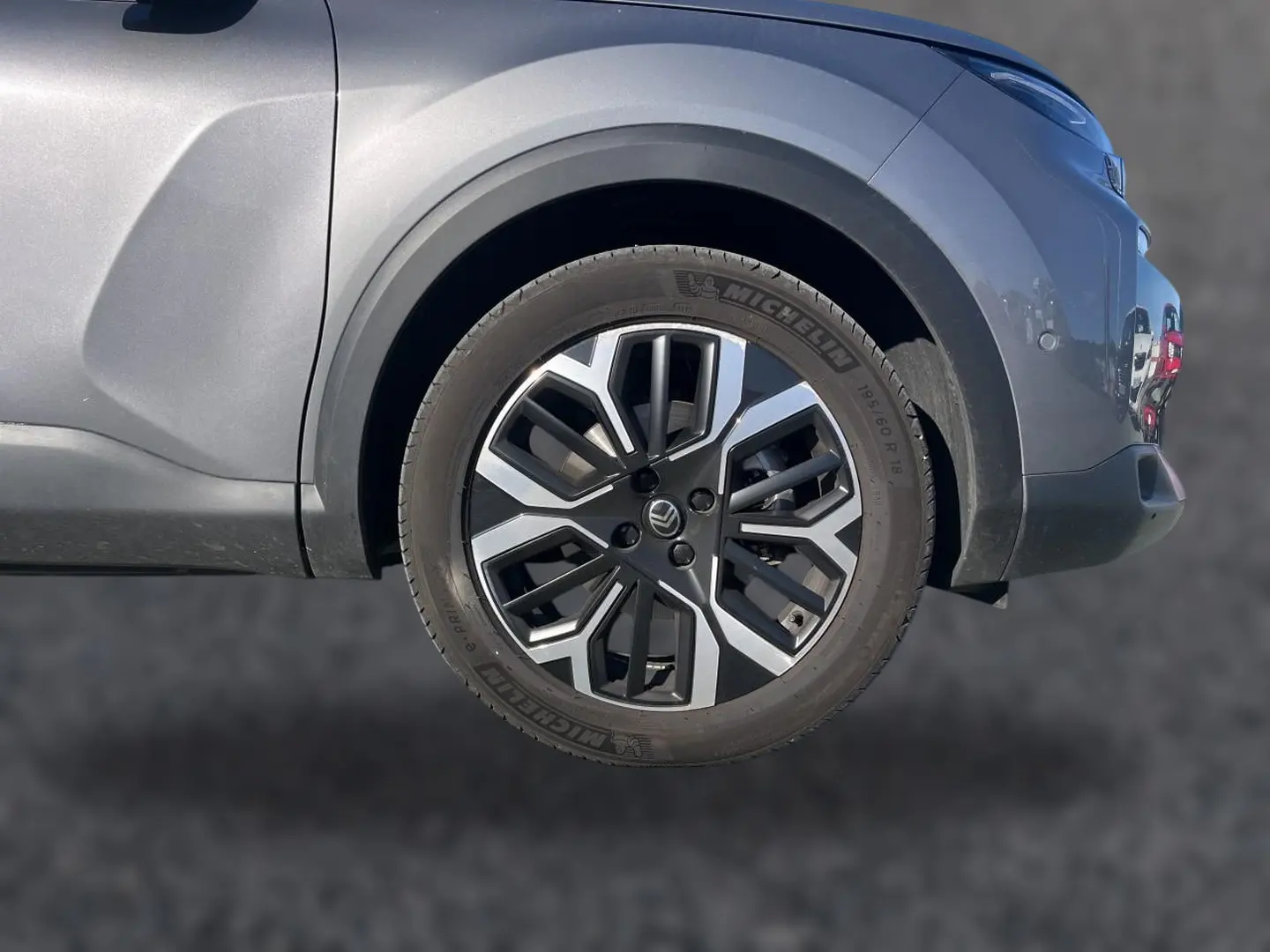Gros plan sur la roue avant droite d'une Citroën C4 X gris mercure avec jante alu au design géométrique.