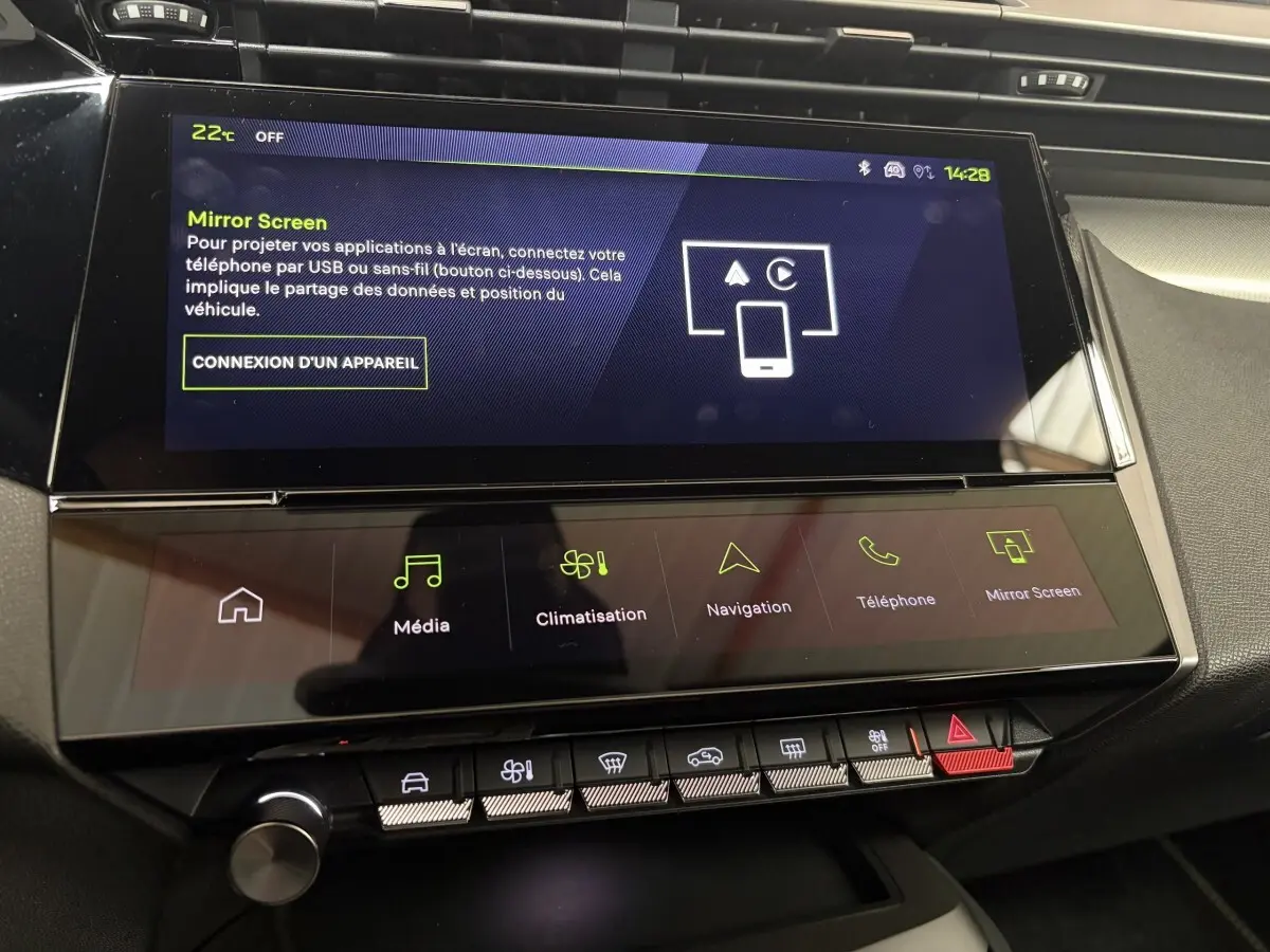 Écran tactile central du tableau de bord de la Peugeot 308 Hybrid 2025 avec interface multimédia et climatisation.