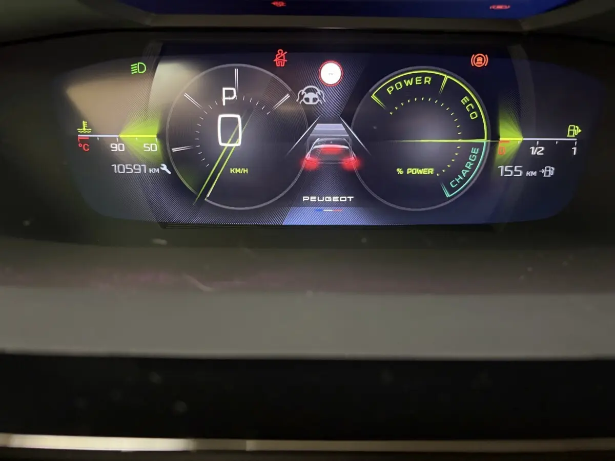 Tableau de bord numérique de la Peugeot 308 hybride, affichant vitesse, autonomie et indicateurs de puissance.