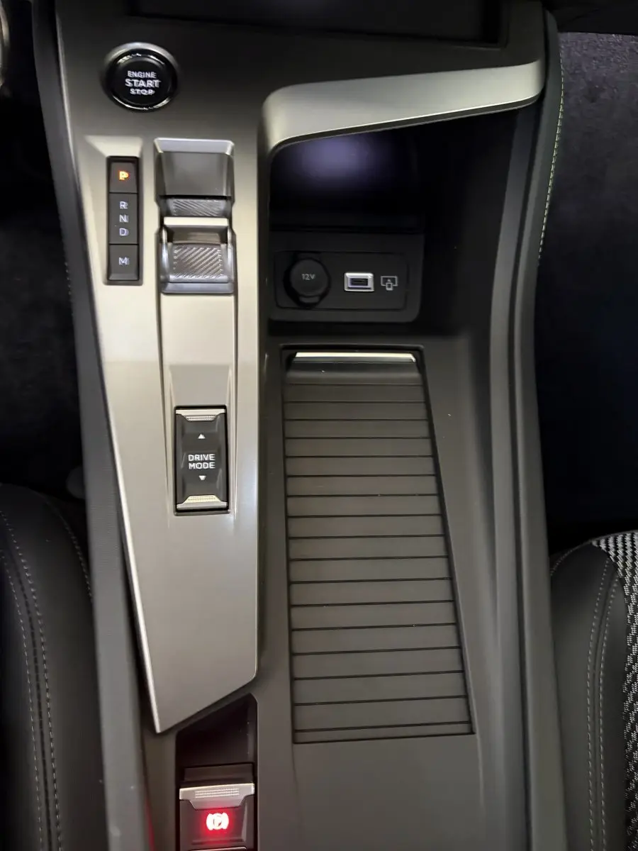 Vue plongeante sur la console centrale noire et grise du Peugeot 308 Hybrid 2025 avec bouton start et commande boîte auto.