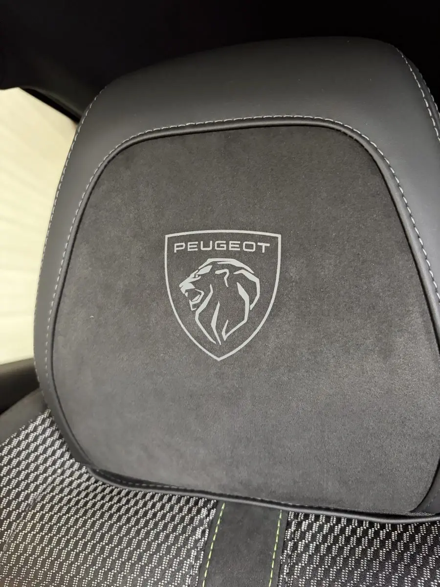 Gros plan sur l'appui-tête noir avec logo Peugeot gravé, sur un siège tissu et cuir de la Peugeot 308 GT.