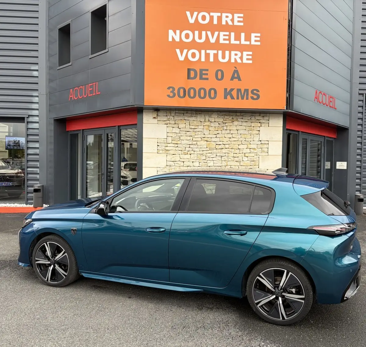 Vue latérale gauche d'une Peugeot 308 1.2 Hybrid 145 GT bleu métallisé, avec jantes alliage et toit panoramique.