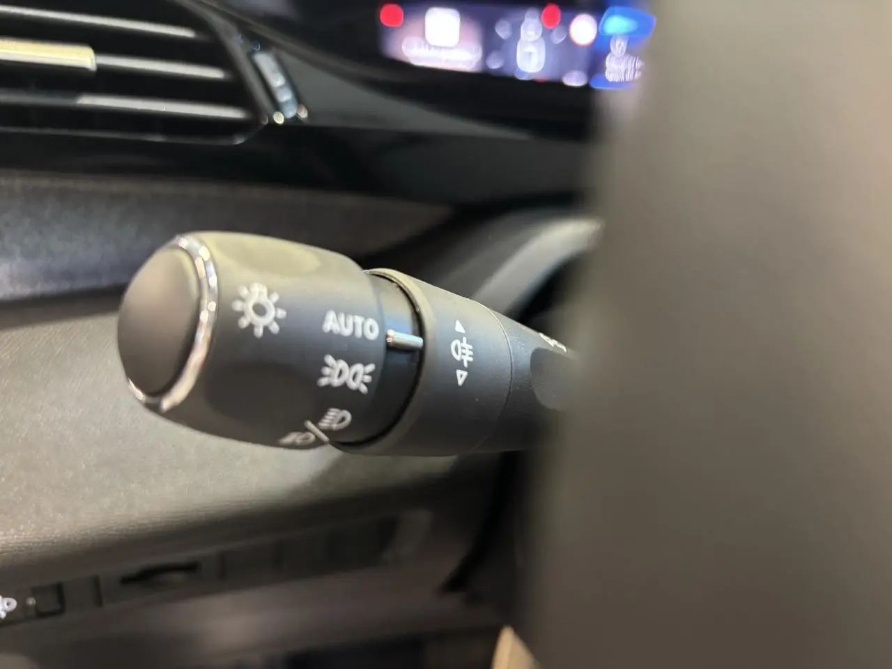 Gros plan sur la commande des feux du tableau de bord d’une Peugeot 308 SW gris clair Metal Artense 2024.