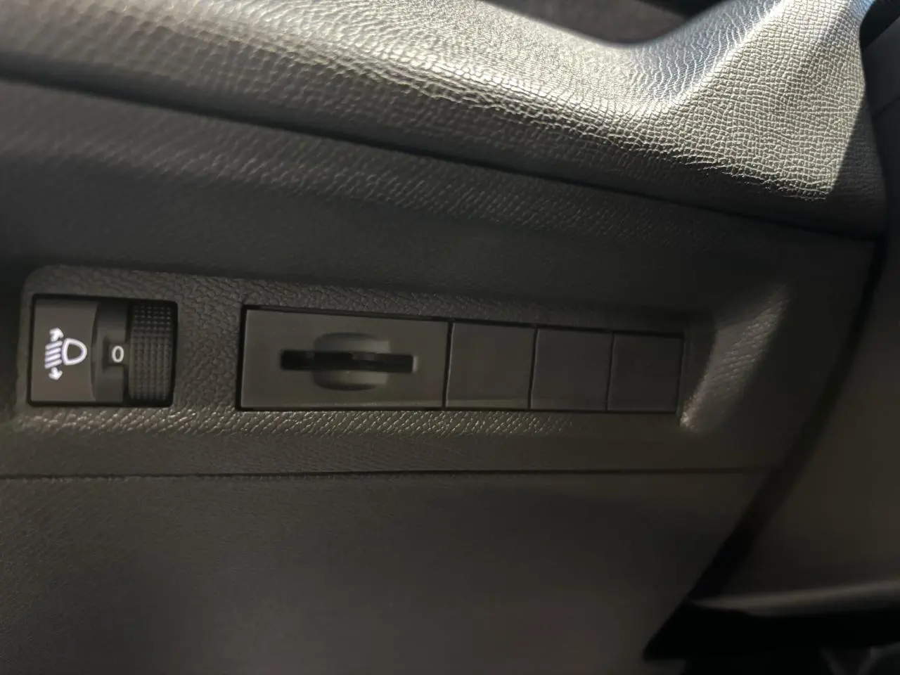 Détail des commandes d’éclairage et réglage du tableau de bord sur la porte côté conducteur d’un Peugeot 308 SW gris clair.