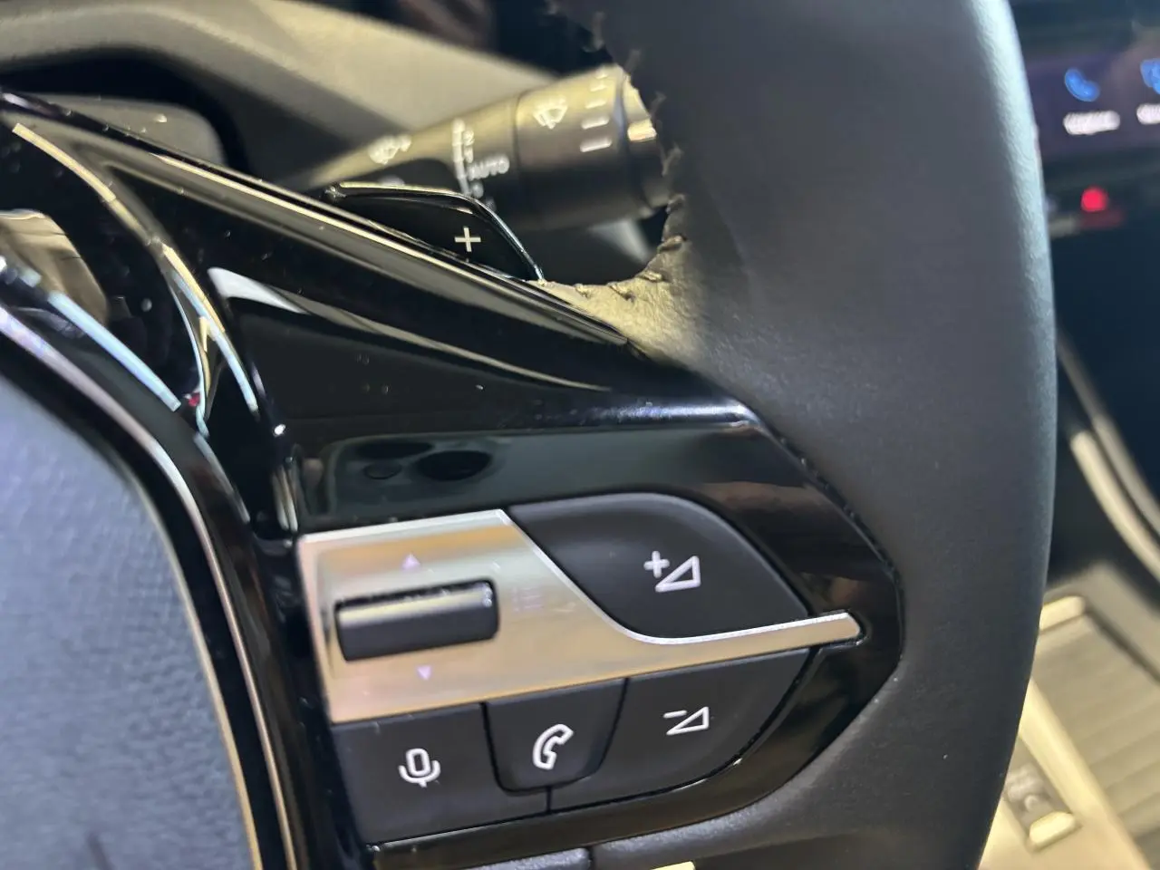 Gros plan sur les commandes multifonctions noires et chromées du volant cuir de la Peugeot 308 SW gris clair métallisé.