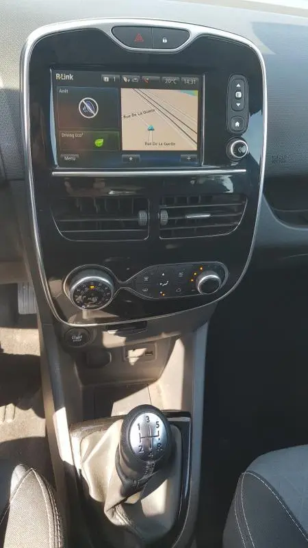 Vue intérieure centrée sur la console centrale et le levier de vitesse manuel d'une Renault Clio IV noire de 2015.