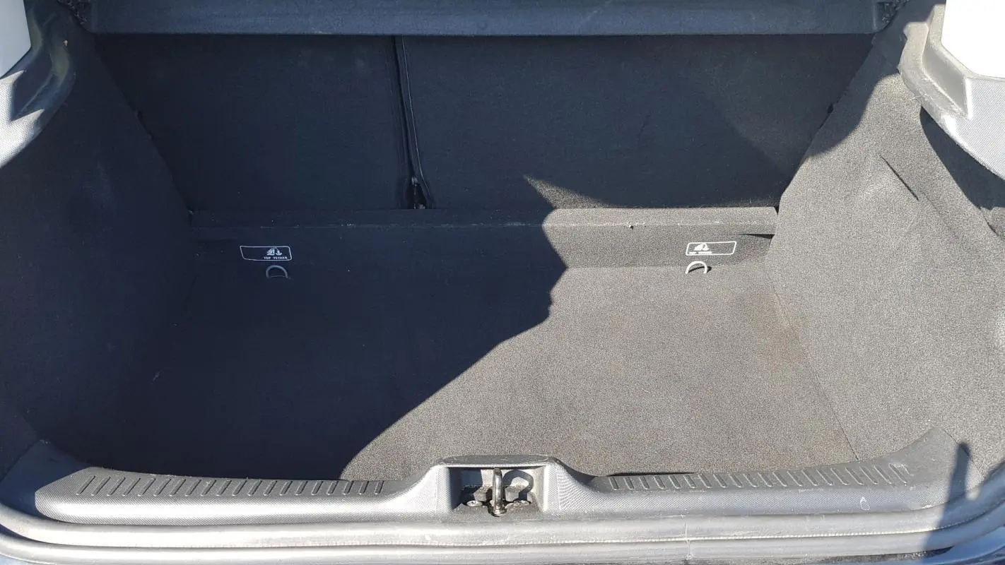 Coffre ouvert d’une Renault Clio IV dCi 90 eco2 Intens noir, montrant l’espace de chargement vide et la moquette noire.