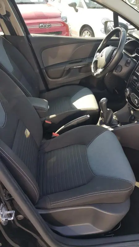 Intérieur avant droit de la Renault Clio IV dCi 90 eco2 Intens 2015 noire, sièges tissu et volant cuir visible.