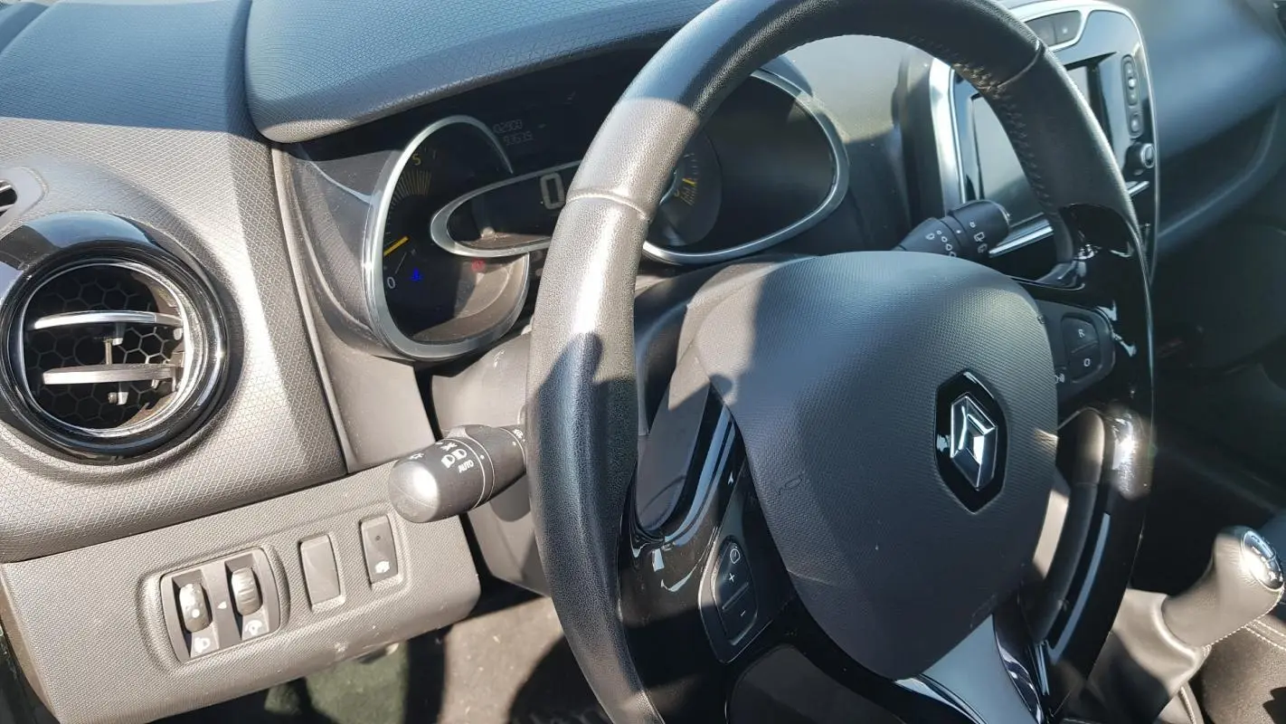 Vue rapprochée de l’intérieur de la Renault Clio IV dCi 90 Intens, volant cuir et tableau de bord noir.
