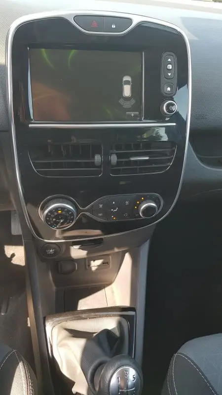 Vue rapprochée du tableau de bord et console centrale noire de la Renault Clio IV dCi 90 eco2 Intens avec écran tactile et levier de vitesse manuel.