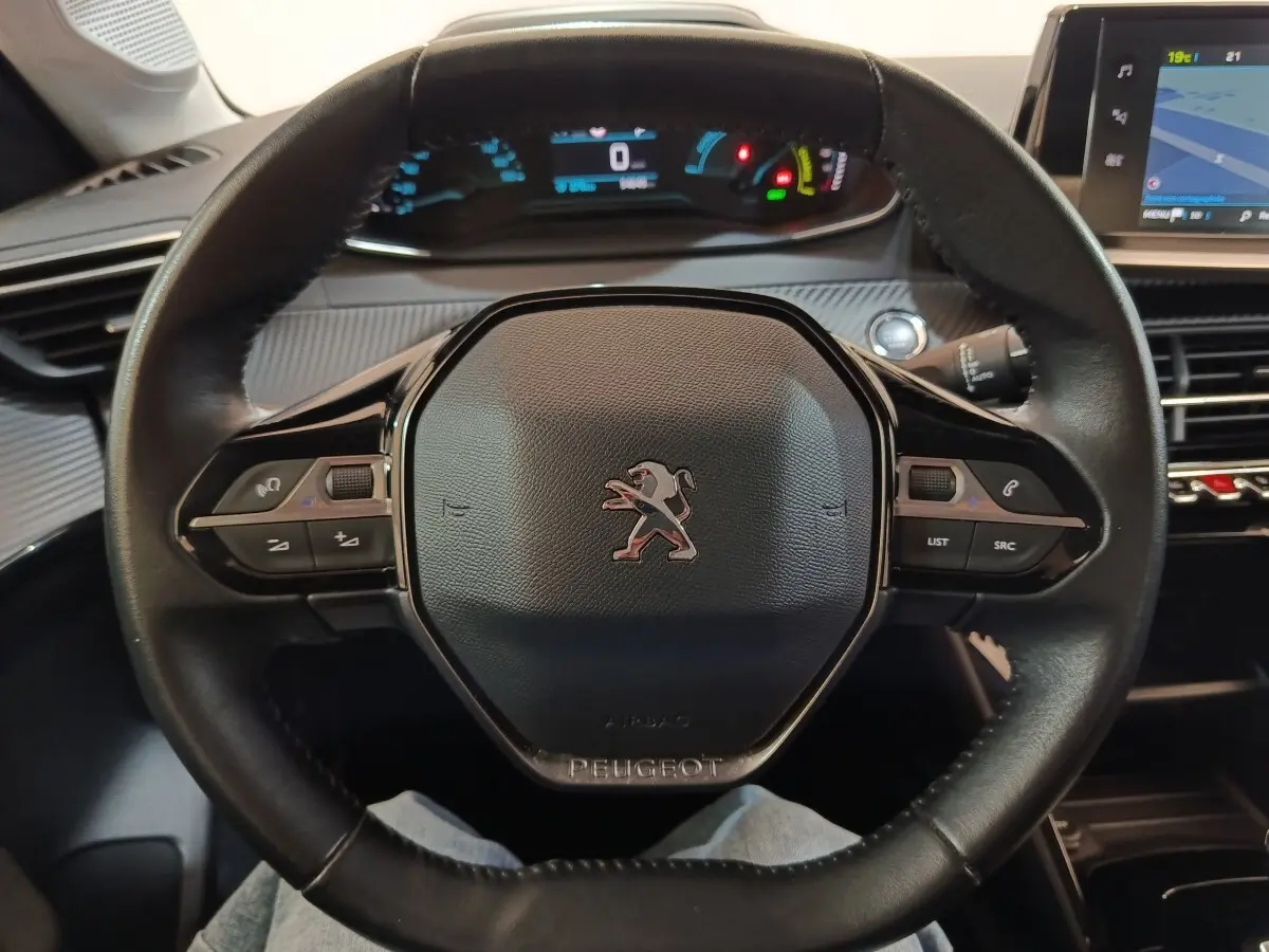 Vue rapprochée du volant cuir noir de la Peugeot 208 électrique Active Business avec tableau de bord digital allumé.