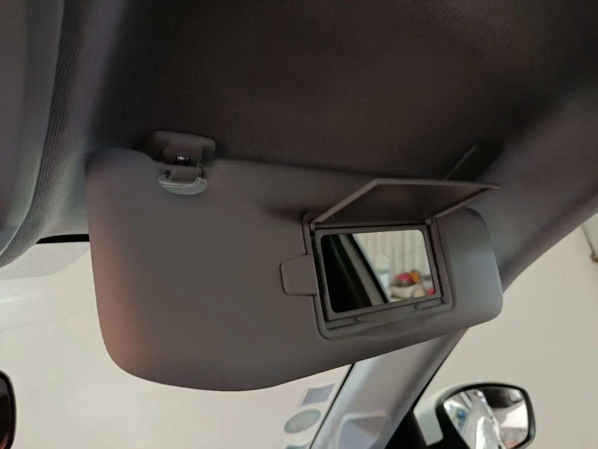 Vue intérieure rapprochée du pare-soleil côté conducteur avec miroir ouvert dans une Peugeot 208 blanche électrique.