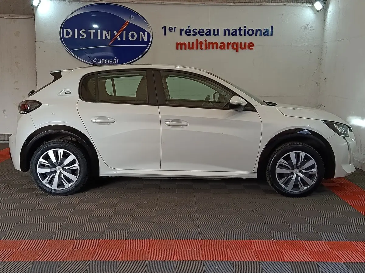 Profil droit d'une Peugeot 208 Electrique Active Business blanche, avec jantes distinctives et logo "e" sur l'aile arrière.