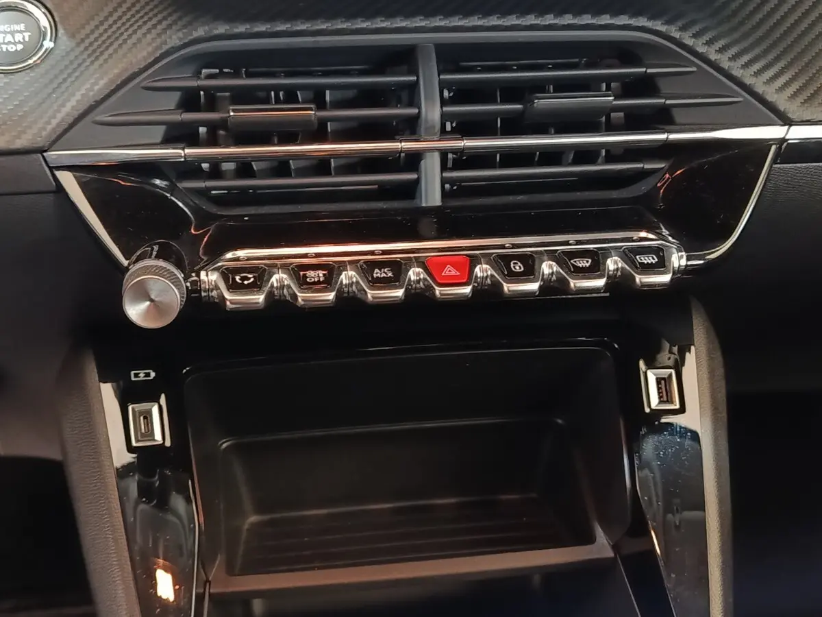 Vue rapprochée du tableau de bord noir de la Peugeot 208 électrique Active Business avec commandes et prises USB visibles.