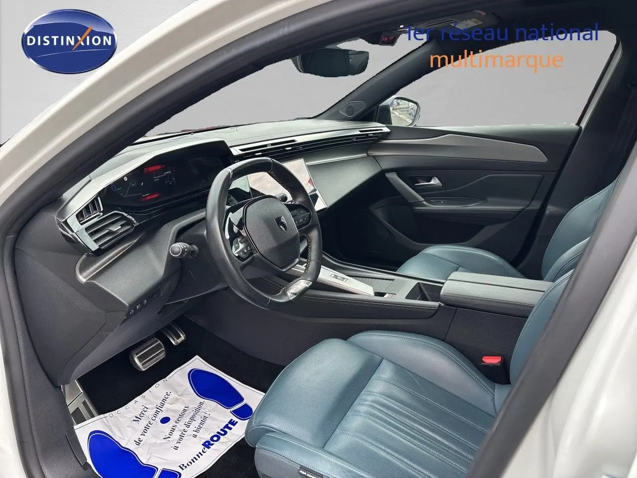 Vue intérieure côté conducteur de la Peugeot 308 SW hybride 2022, sièges cuir bleu et tableau de bord moderne.
