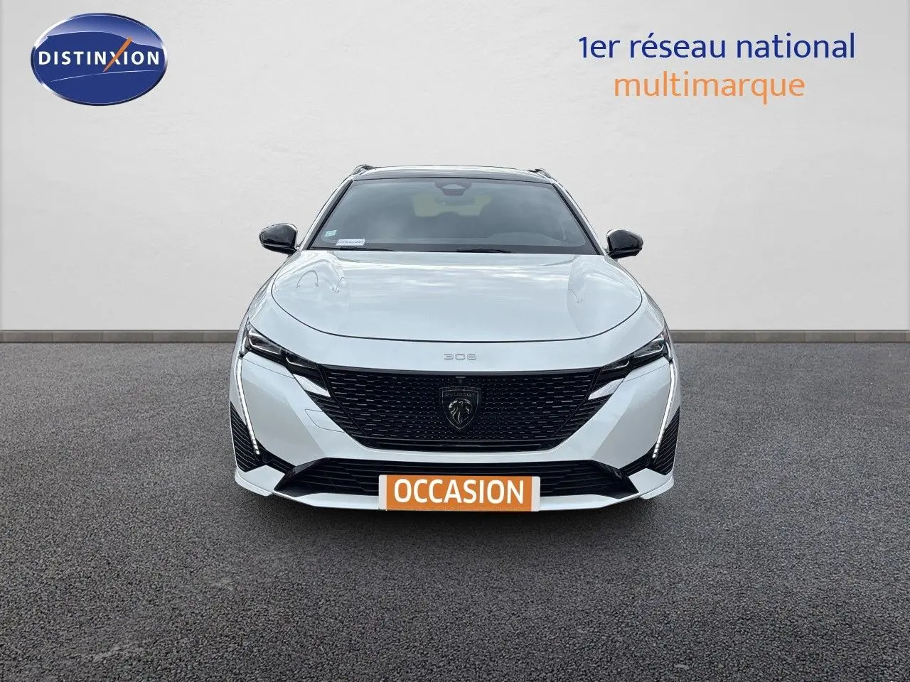 Vue frontale d'une Peugeot 308 SW hybride blanche nacrée métal avec calandre noire et phares LED distinctifs.