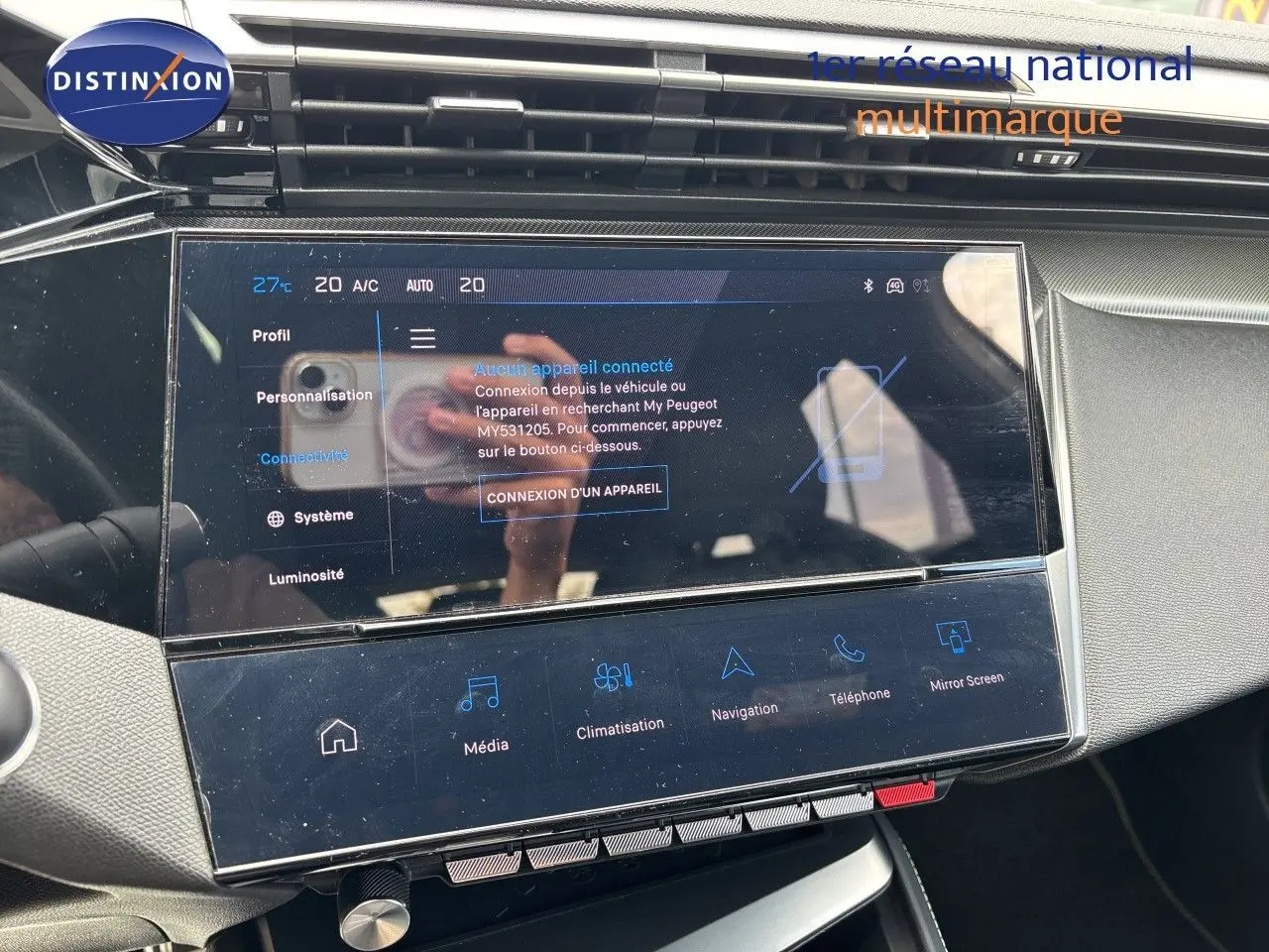 Vue rapprochée de l'écran tactile central du tableau de bord de la Peugeot 308 SW hybride blanche, affichant les options de connectivité.