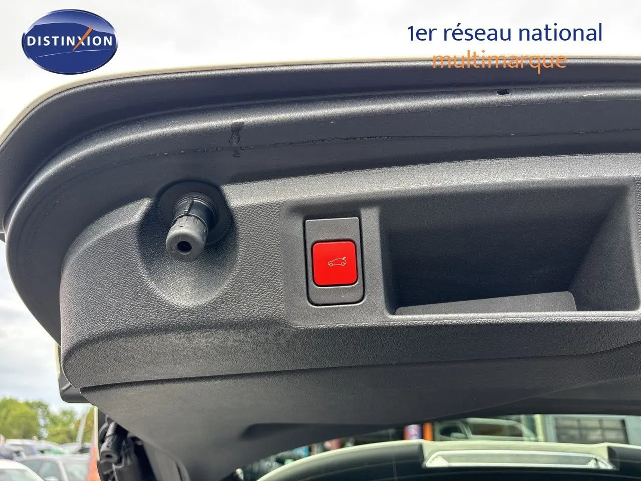 Bouton rouge d'ouverture électrique du hayon sur le bord intérieur du coffre d'une Peugeot 308 SW blanc nacré métal.