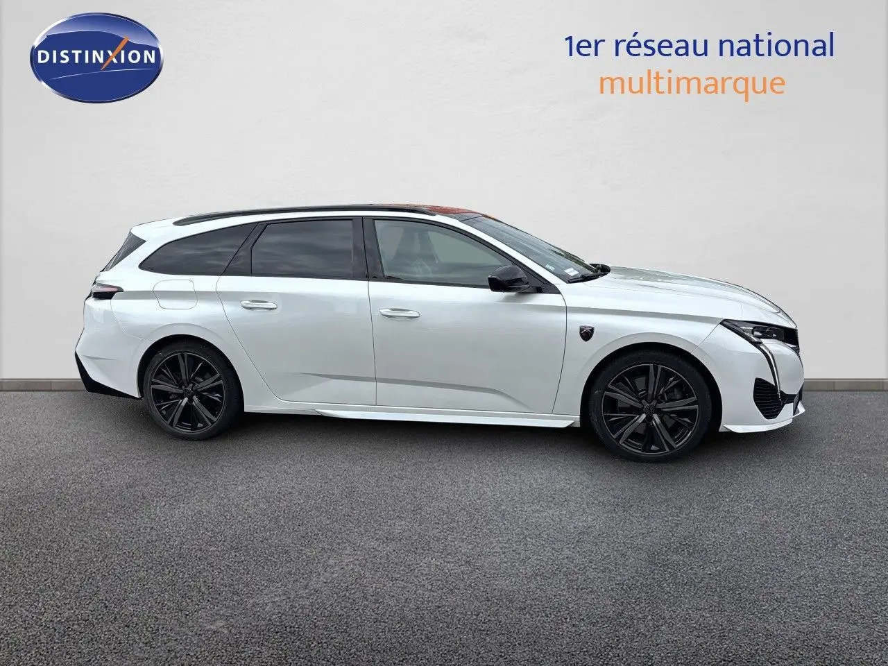Peugeot 308 SW hybride blanc nacré, vue de profil côté gauche, jantes noires et vitres teintées.