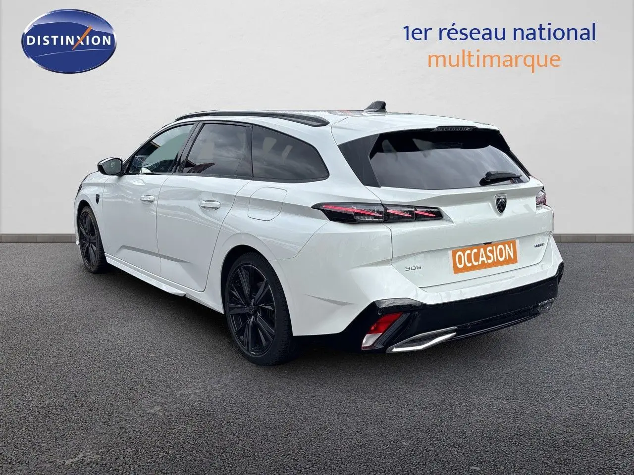 Peugeot 308 SW hybride blanc nacré, vue 3/4 arrière droit, jantes noires et feux arrière LED distinctifs.