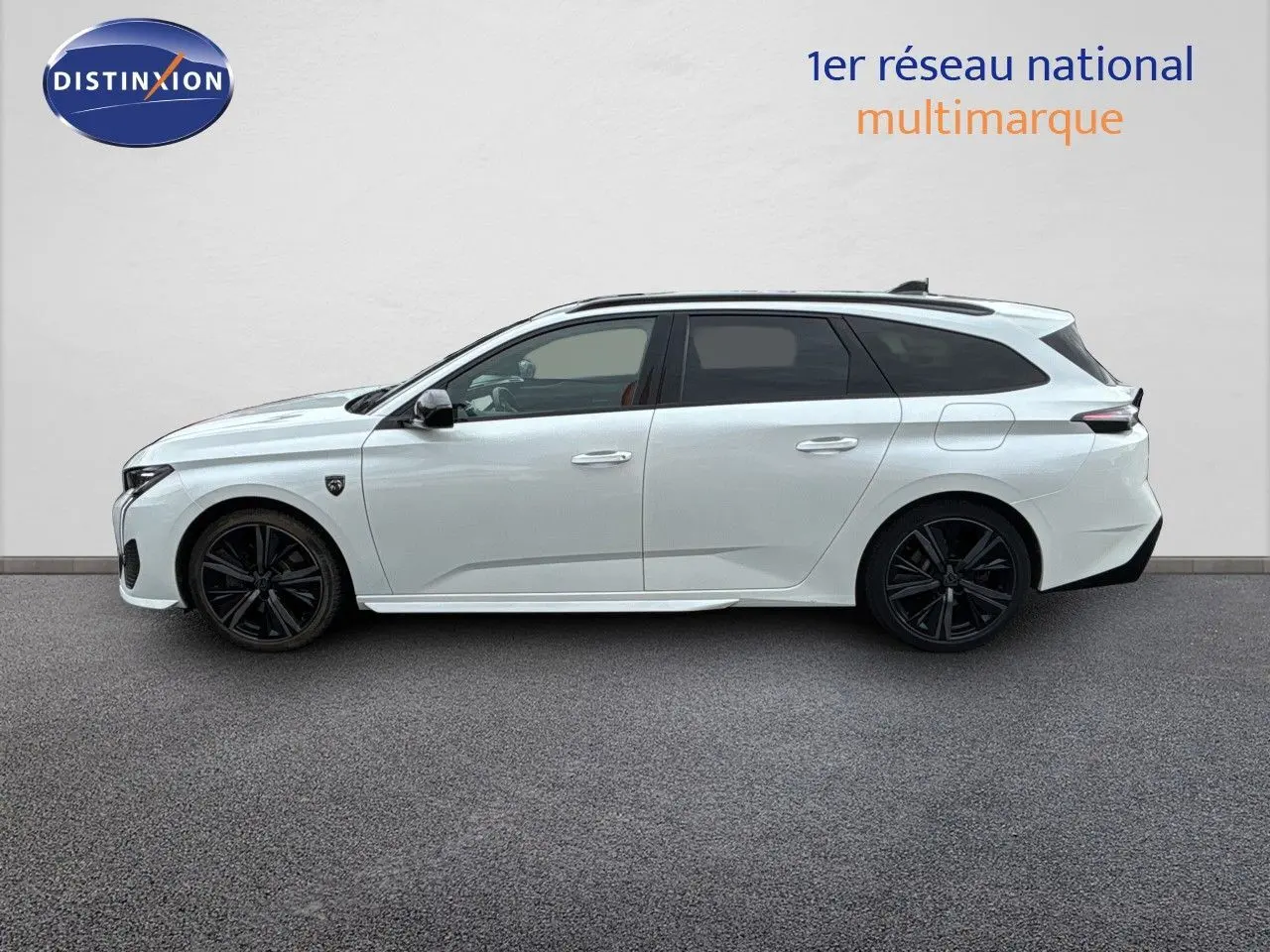 Profil côté gauche d'une Peugeot 308 SW hybride blanche nacrée avec jantes noires et toit panoramique.