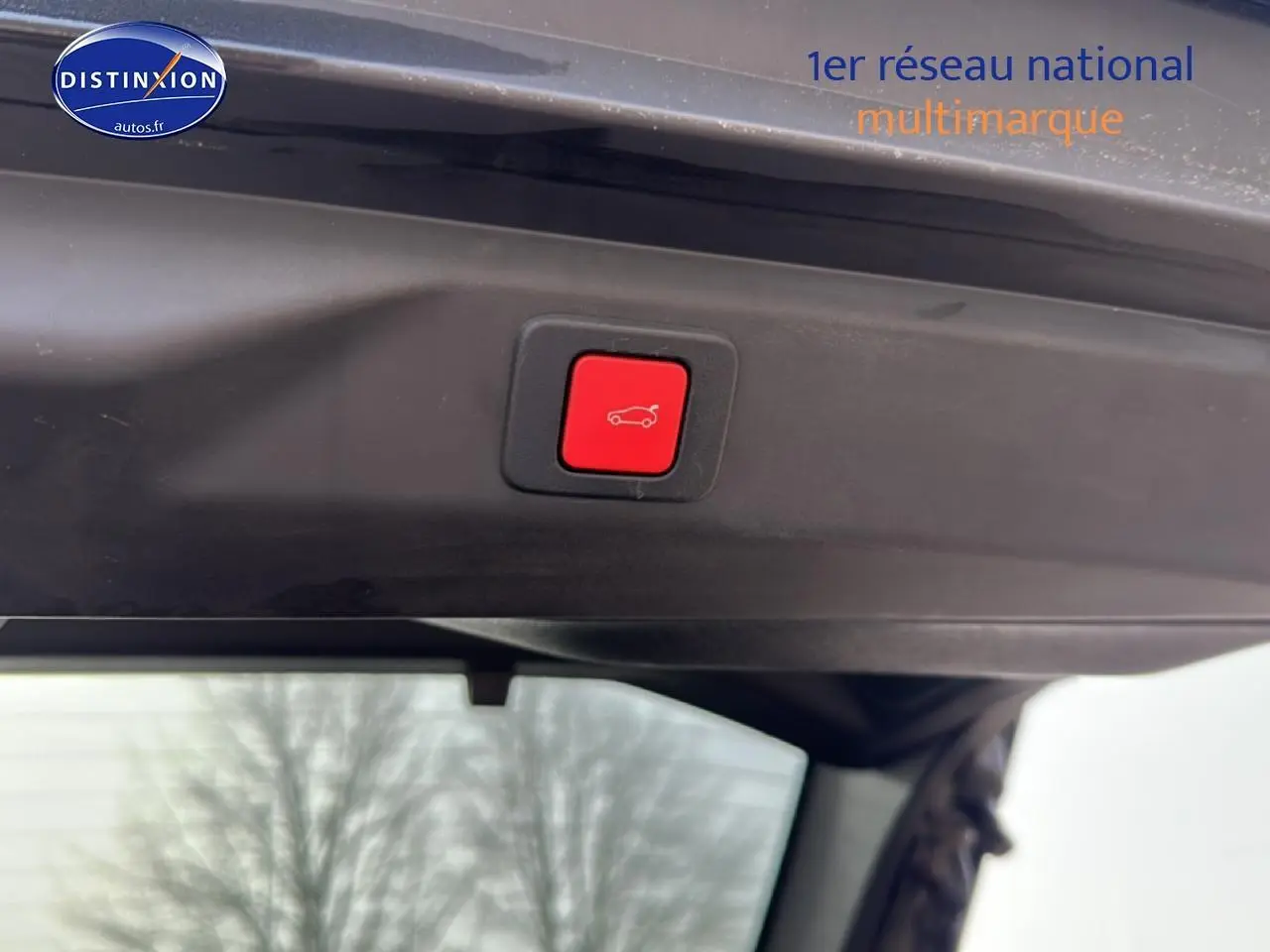Bouton rouge d'ouverture électrique du coffre sur la partie intérieure du hayon d'un Peugeot 3008 gris Artense.