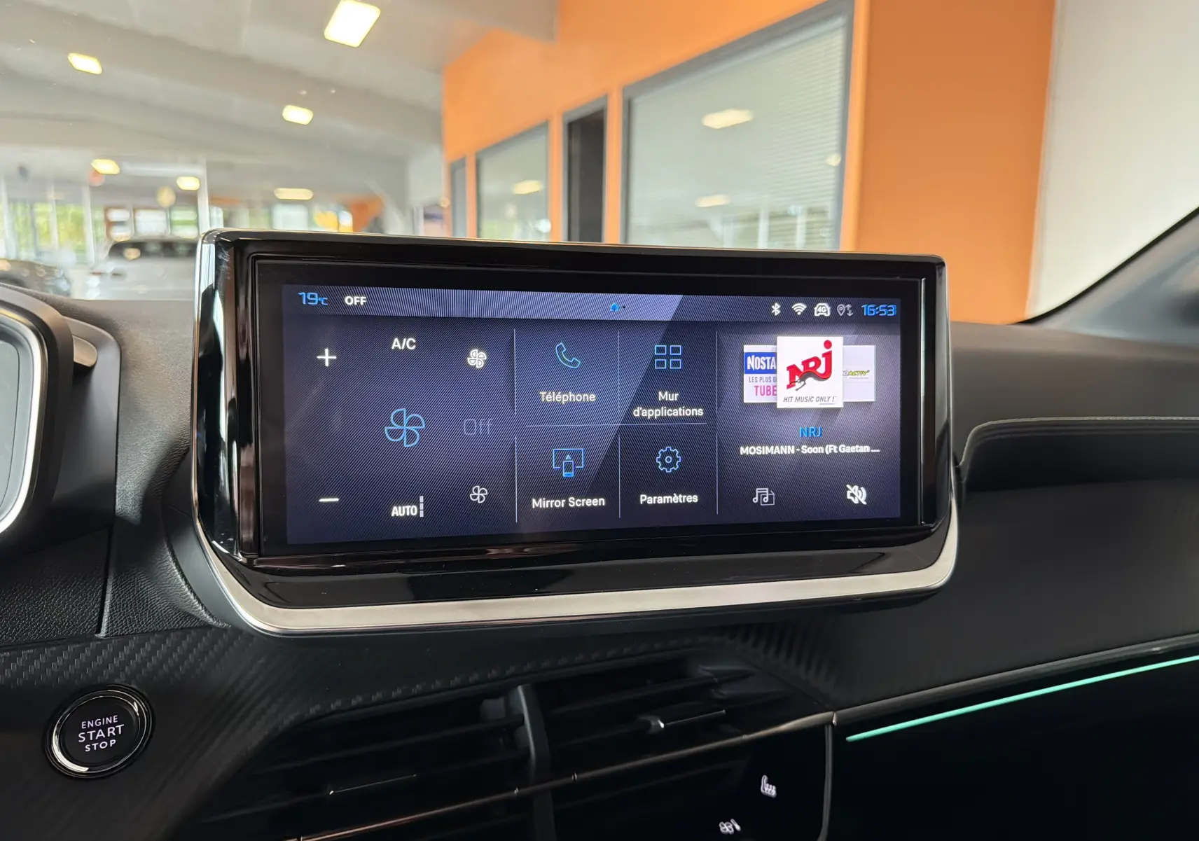Écran tactile central de la Peugeot 208 Hybrid 145 GT 2025, intérieur noir avec éclairage d’ambiance vert.