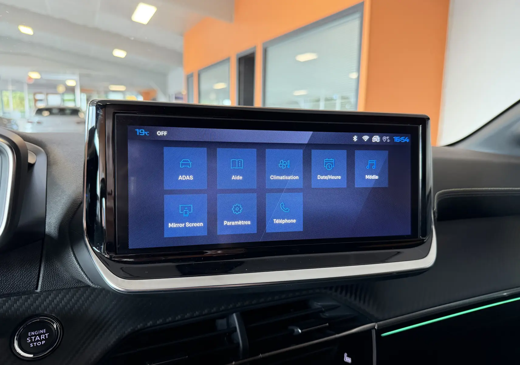 Écran tactile central de la Peugeot 208 Hybrid 145 GT 2025, affichant le menu principal dans un intérieur noir moderne.