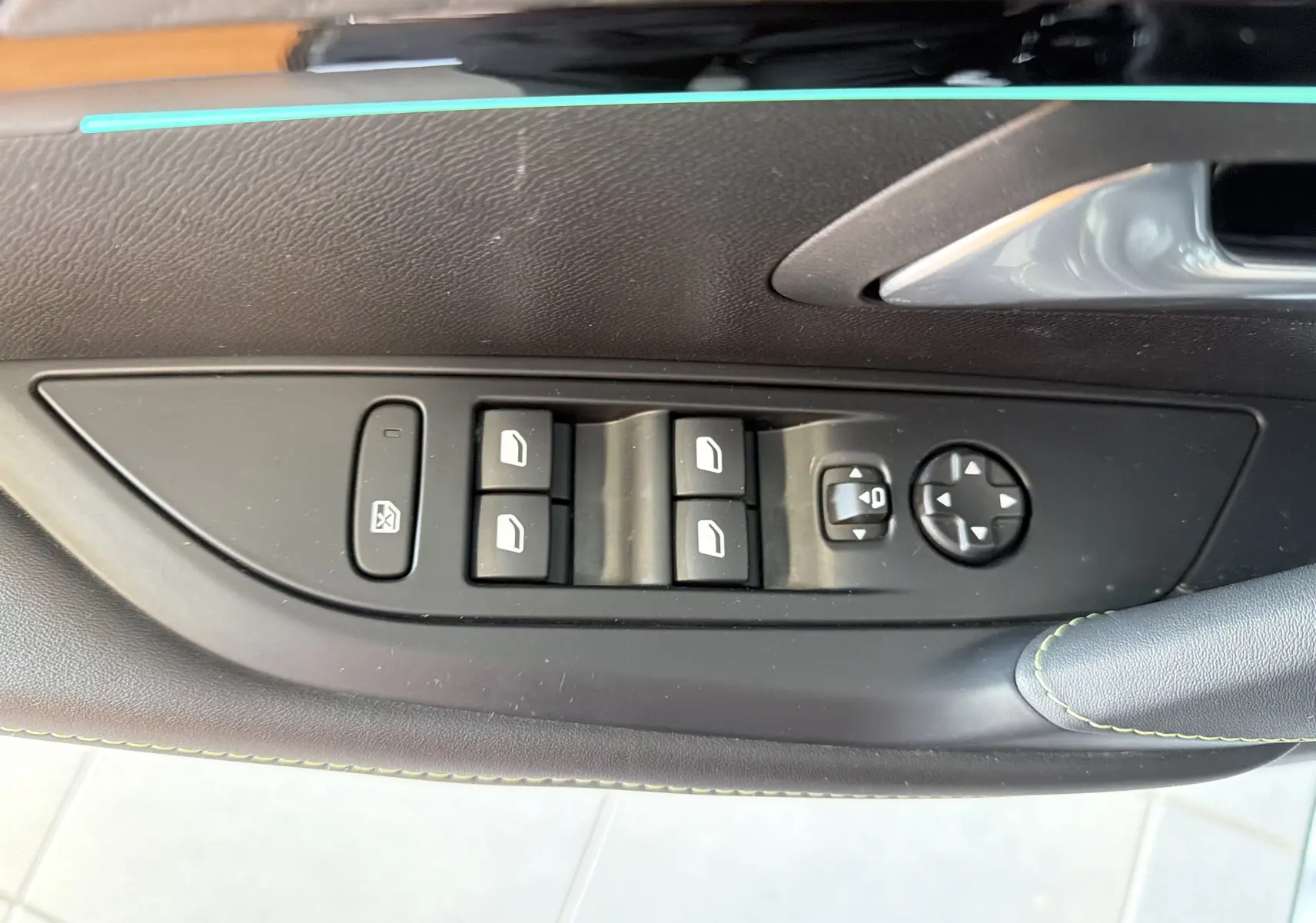 Détail de la commande des vitres et réglages des rétroviseurs sur la porte côté gauche d’une Peugeot 208 Hybrid 145 GT noire.