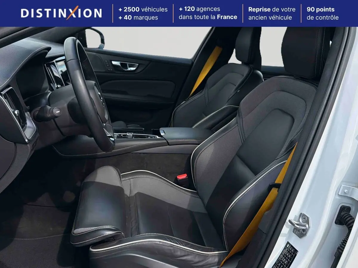 Intérieur avant droit d'une Volvo S60 blanche 2021 avec sièges sport cuir/tissu anthracite et ceintures jaunes.