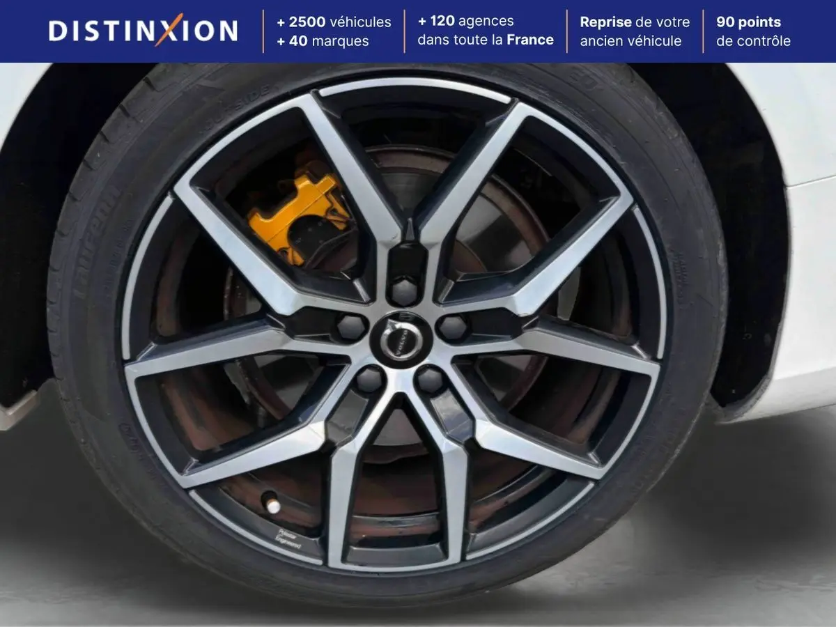 Gros plan sur la jante alliage 19 pouces style Y noir et argent avec étrier de frein jaune sur Volvo S60 blanche.