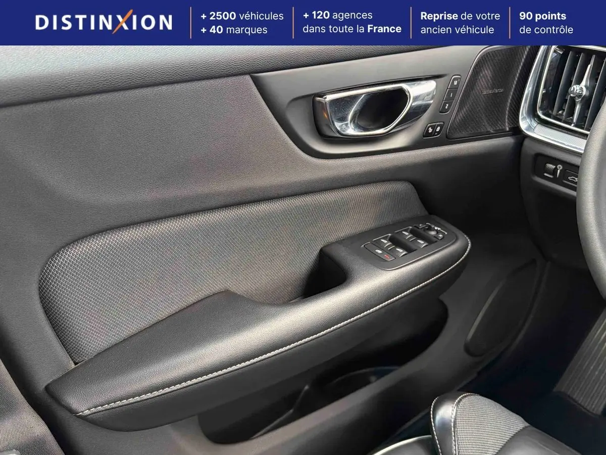 Détail de la porte avant gauche intérieure d’une Volvo S60 blanche, avec commandes de vitres et insert haut-parleur Harman Kardon.
