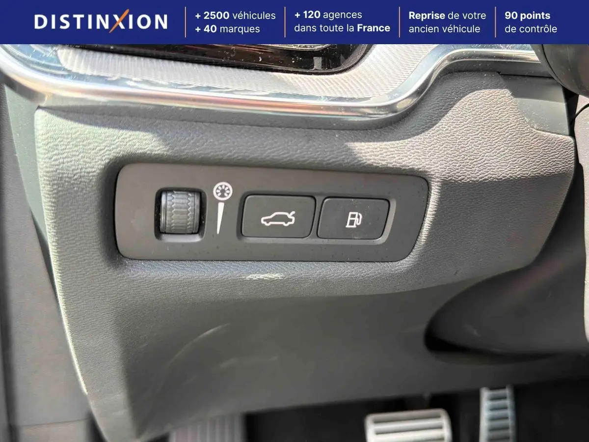Gros plan sur les commandes d'ouverture du coffre et de la trappe à carburant dans l'habitacle d'une Volvo S60 blanche.