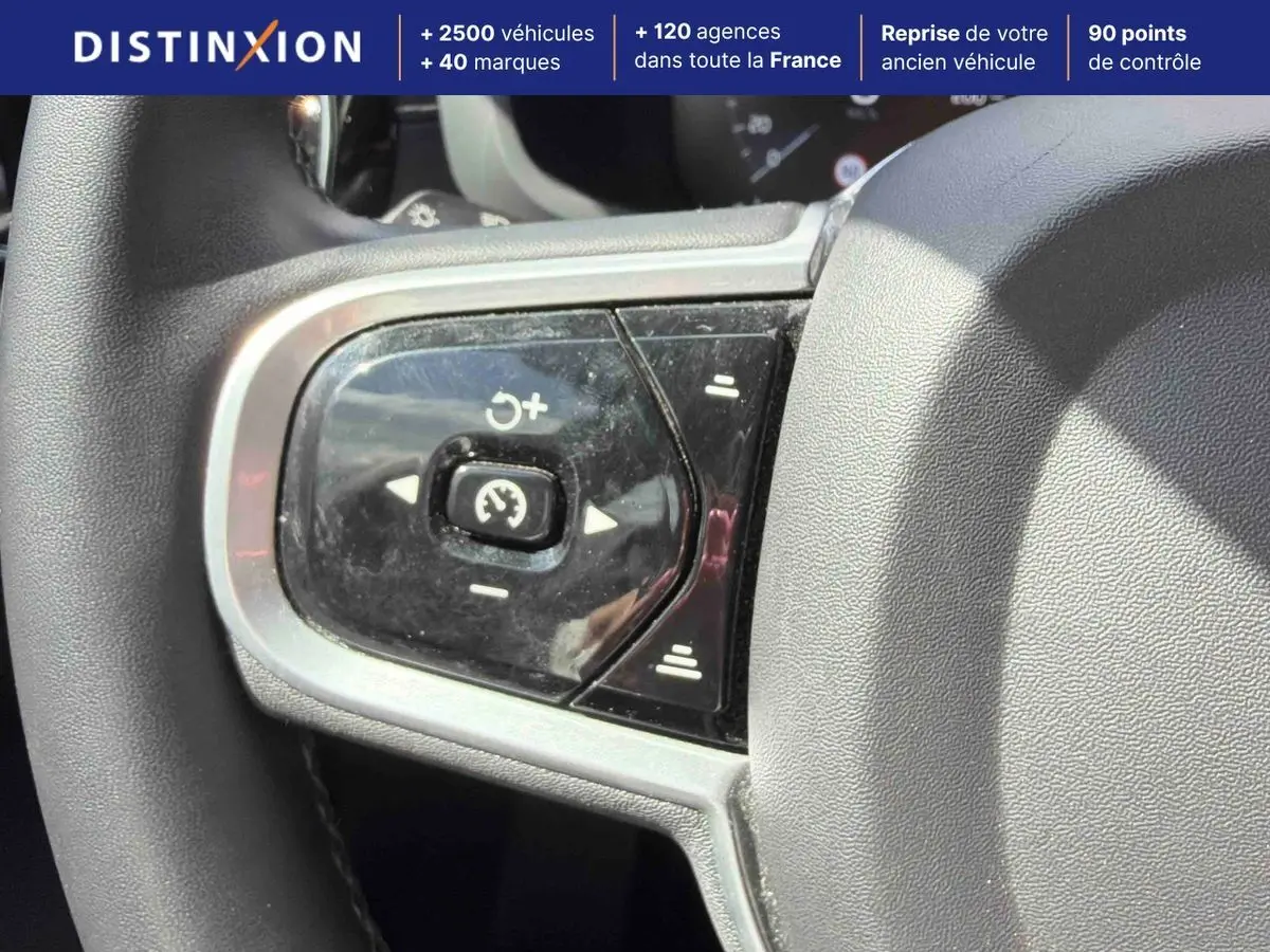 Gros plan sur les commandes de régulateur de vitesse au volant d'une Volvo S60 blanche, intérieur lumineux.