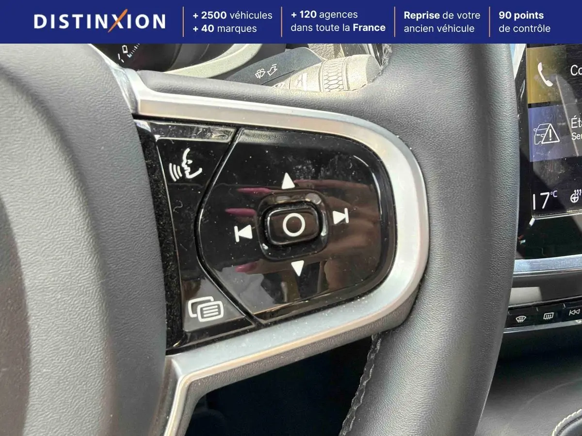 Gros plan sur les commandes vocales et multimédia au volant d'une Volvo S60 blanche, intérieur moderne avec écran tactile visible.