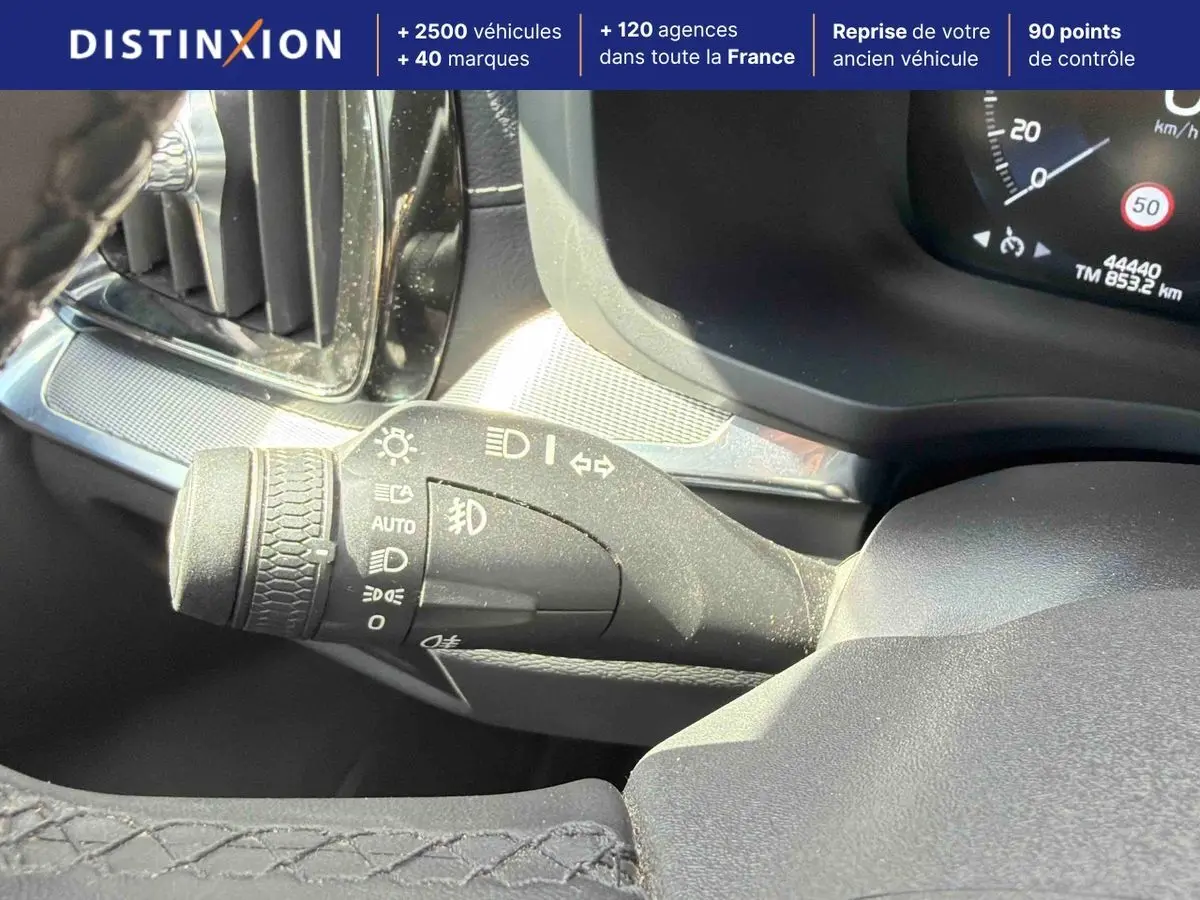 Gros plan sur la commande des feux à gauche du volant dans l’habitacle du Volvo S60 blanc de 2021.