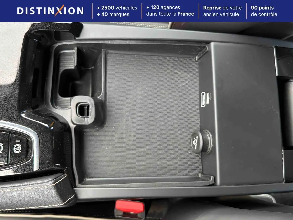 Vue rapprochée de la console centrale noire du Volvo S60 T8 blanc, avec levier de vitesses manuel et rangement ouvert.