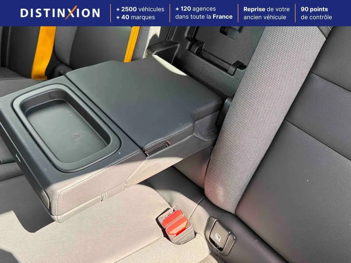 Détail de l'accoudoir central arrière noir et sellerie tissu/cuir anthracite avec ceintures de sécurité jaunes sur Volvo S60 blanche.