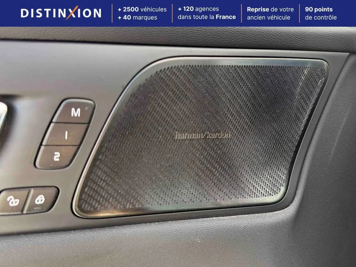Détail du haut-parleur Harman Kardon et commandes de porte côté conducteur d’une Volvo S60 blanche.
