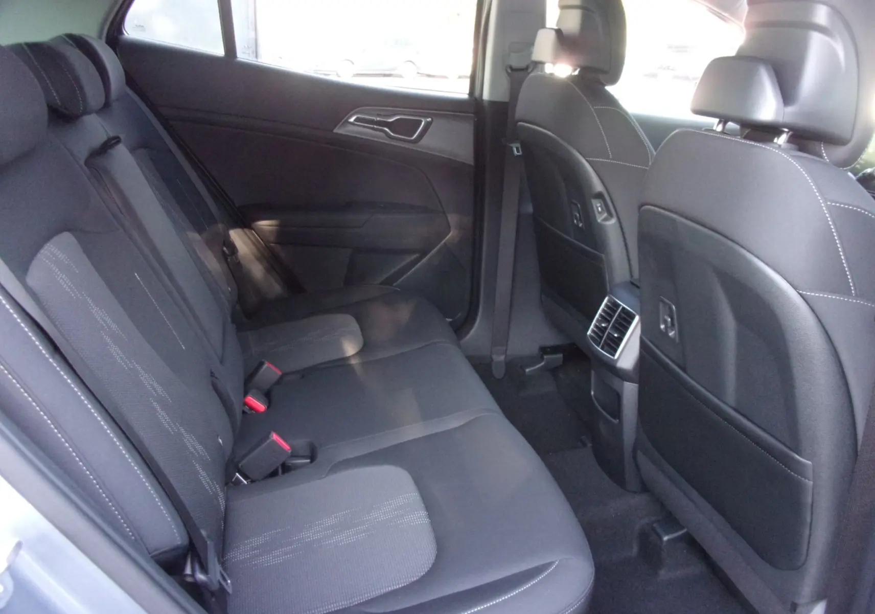 Vue intérieure arrière côté droit du Kia Sportage 2025 gris perle, montrant les sièges arrière et les aérateurs centraux.