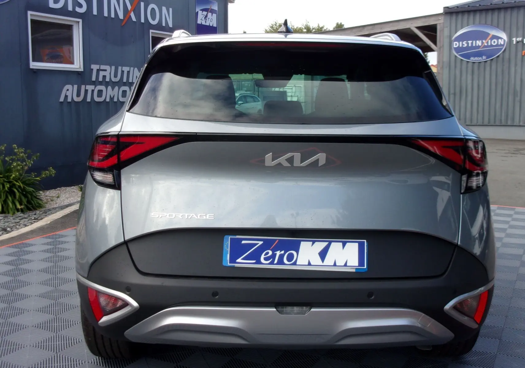 Vue arrière d'un KIA SPORTAGE gris perle 2025 avec feux arrière LED et logo KIA moderne visible.