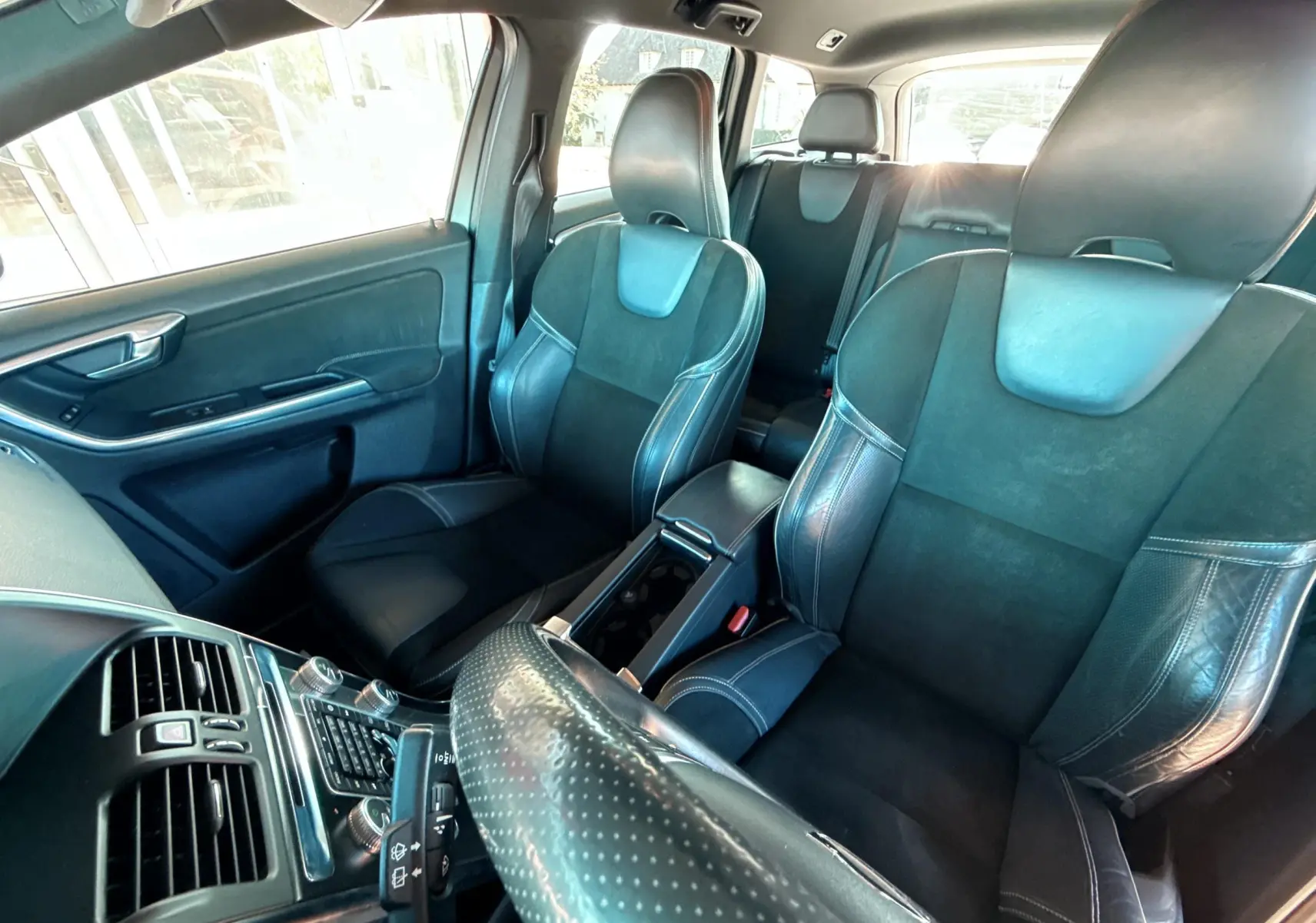 Vue intérieure avant du Volvo XC60 gris 2016 montrant sièges sport en cuir noir et console centrale.