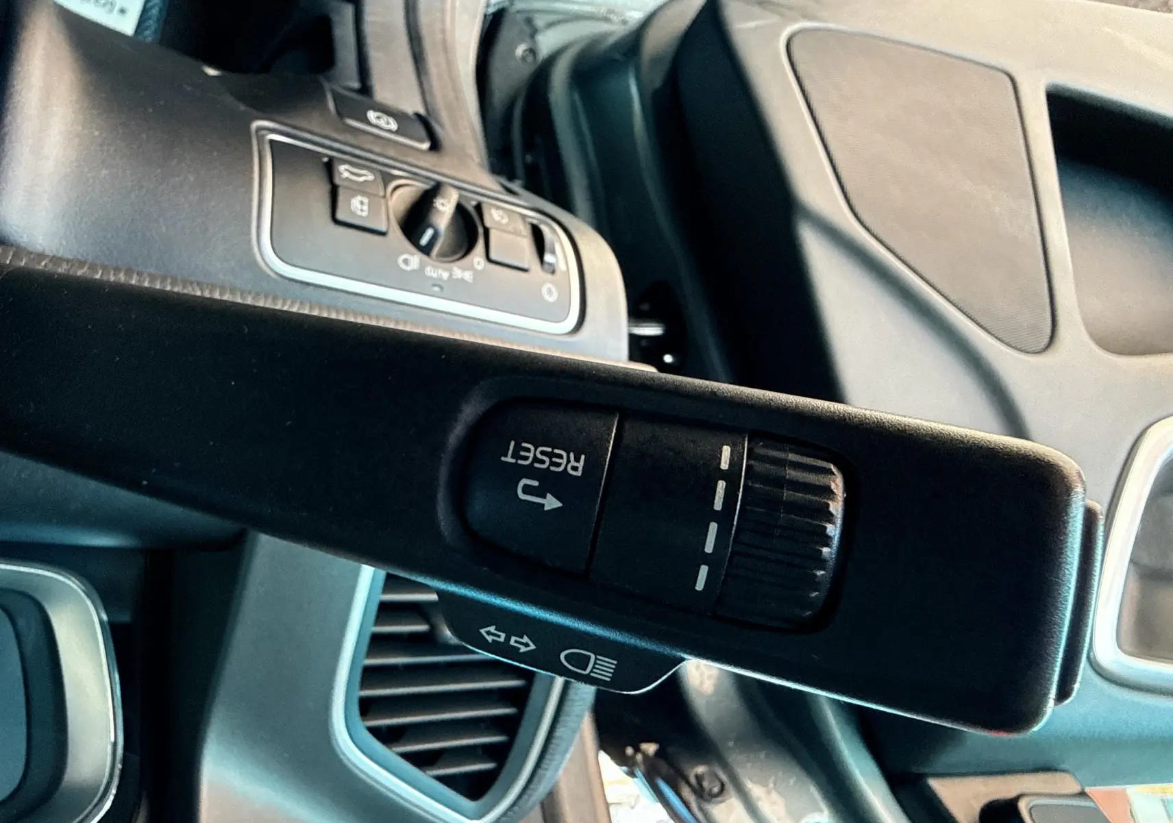 Gros plan sur la commande de réinitialisation au volant du Volvo XC60 gris, intérieur moderne et épuré visible en arrière-plan